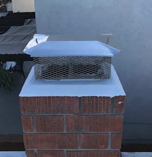 New rectangular chimney cap with animal guard on a red brick chimney.