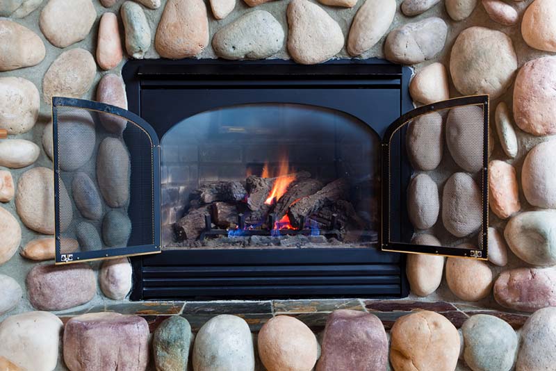 Lit fireplace with a rock surround