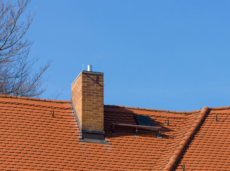 Brick chimney on a red roof
